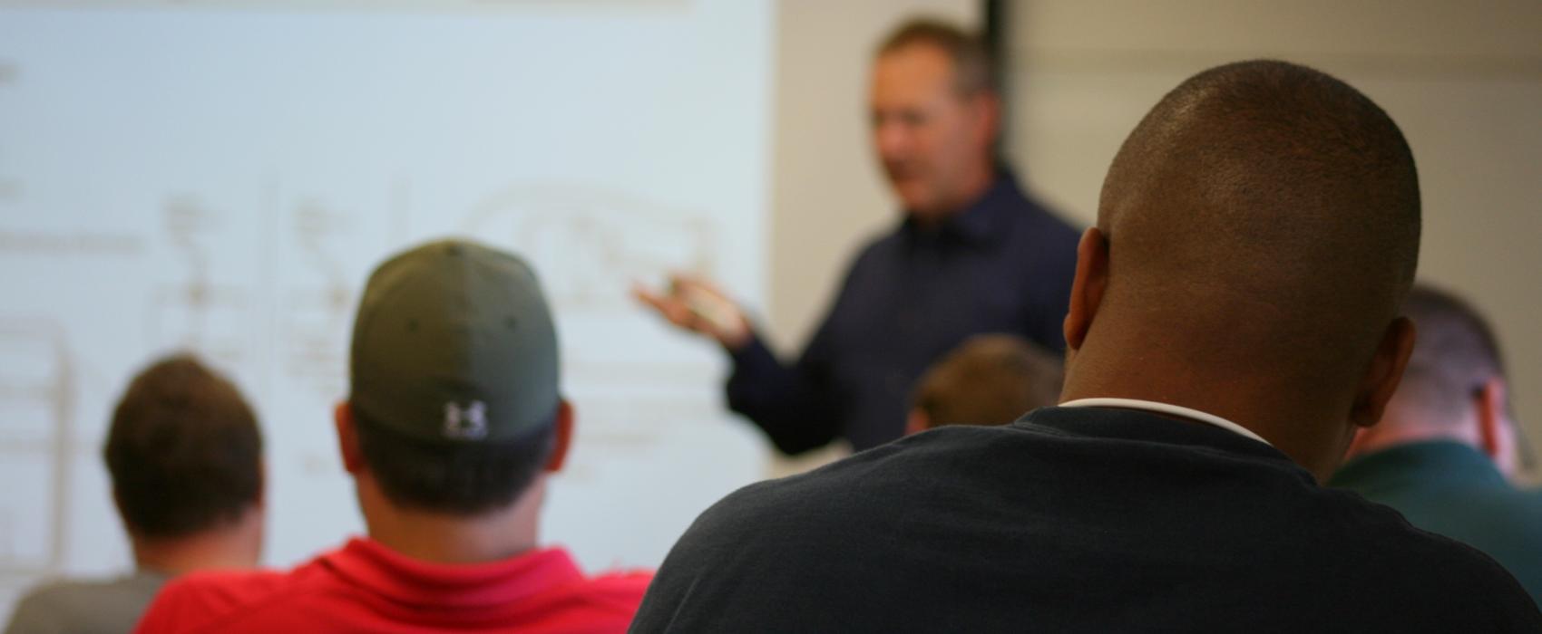 An instructor presents slides in front of a classroom of students